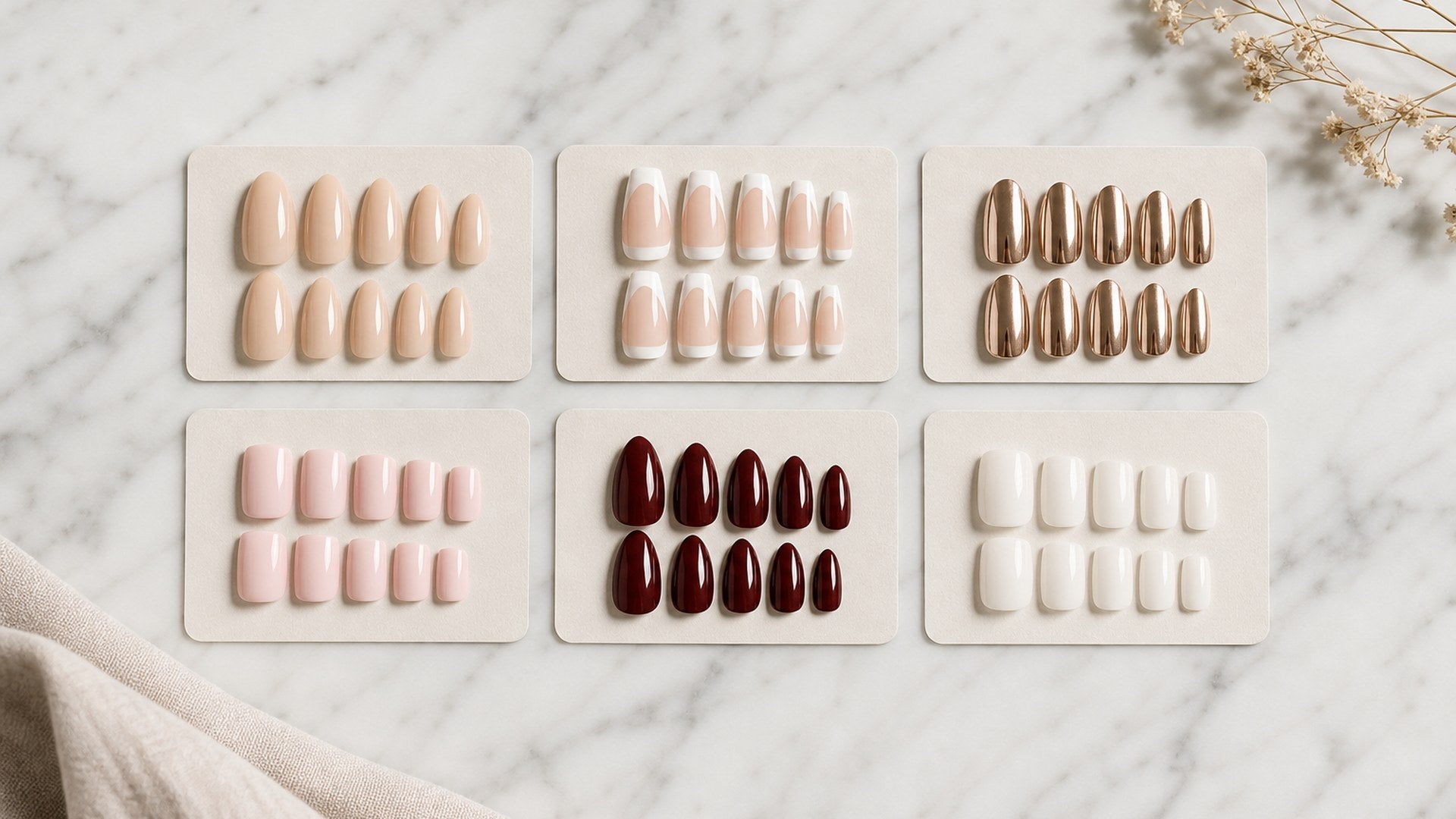 six press-on nail sets in different styles arranged side by side on marble for a brand comparison