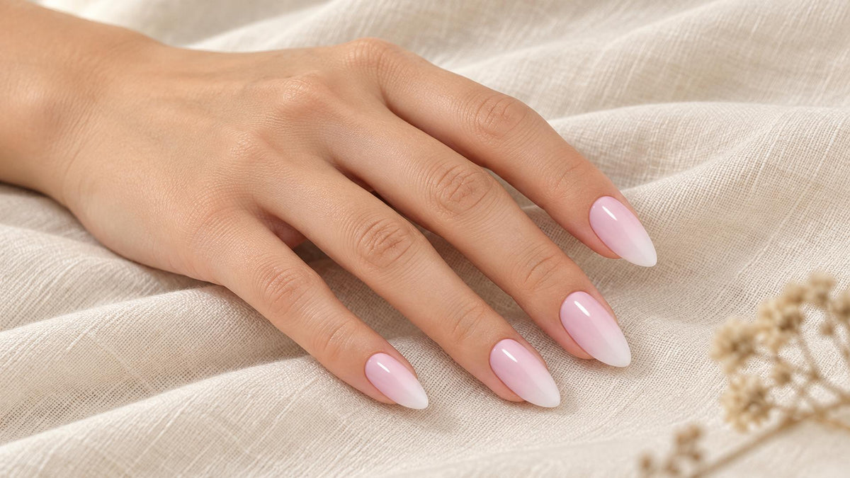 medium almond press-on nails on a hand, glossy soft pink ombre tips with a clean tapered almond point