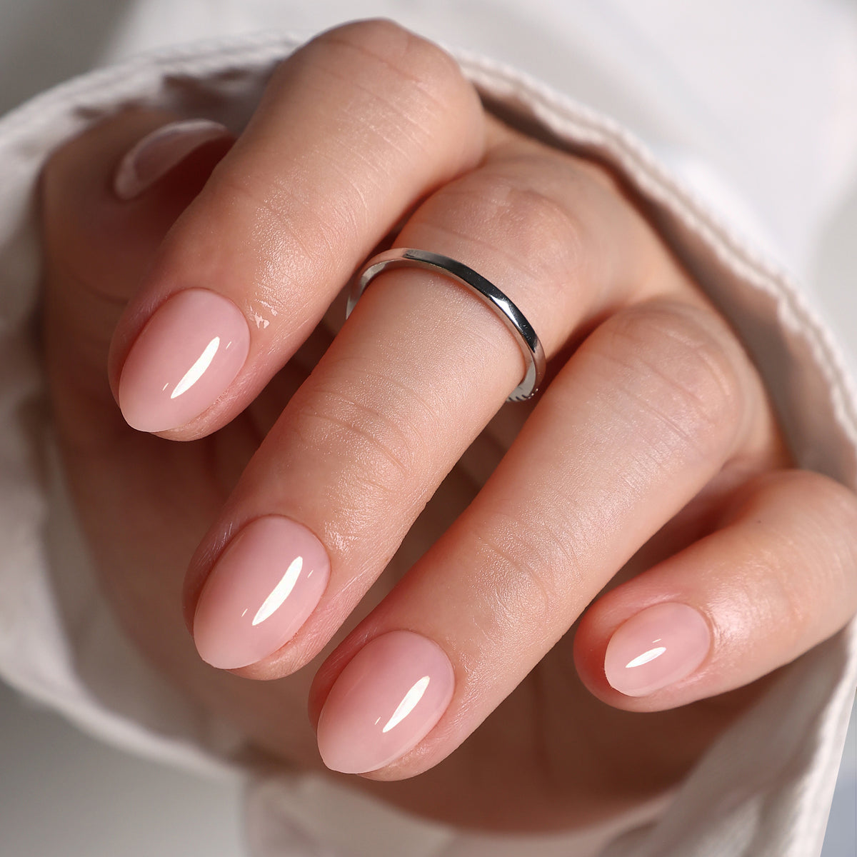 Soft Whisper Nude unhas press-on amendoadas extra curtas: close do acabamento brilhante na mão | SHANGMENG®